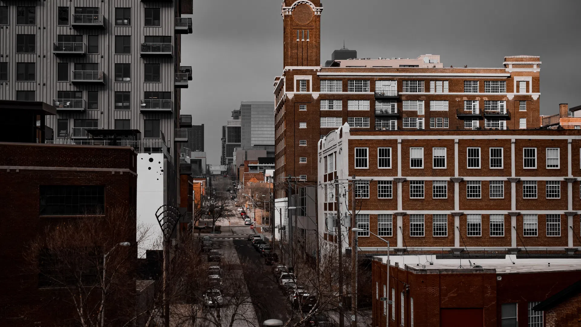 Urban street view with red brick historic buildings and modern apartments under a gray sky.