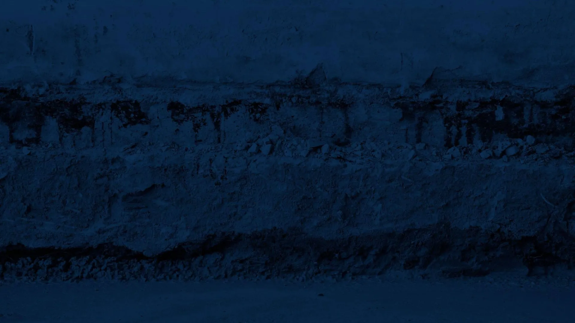 Dark textured blue wall with cracked paint and rough stone beneath, showing weathered, aged surface details.