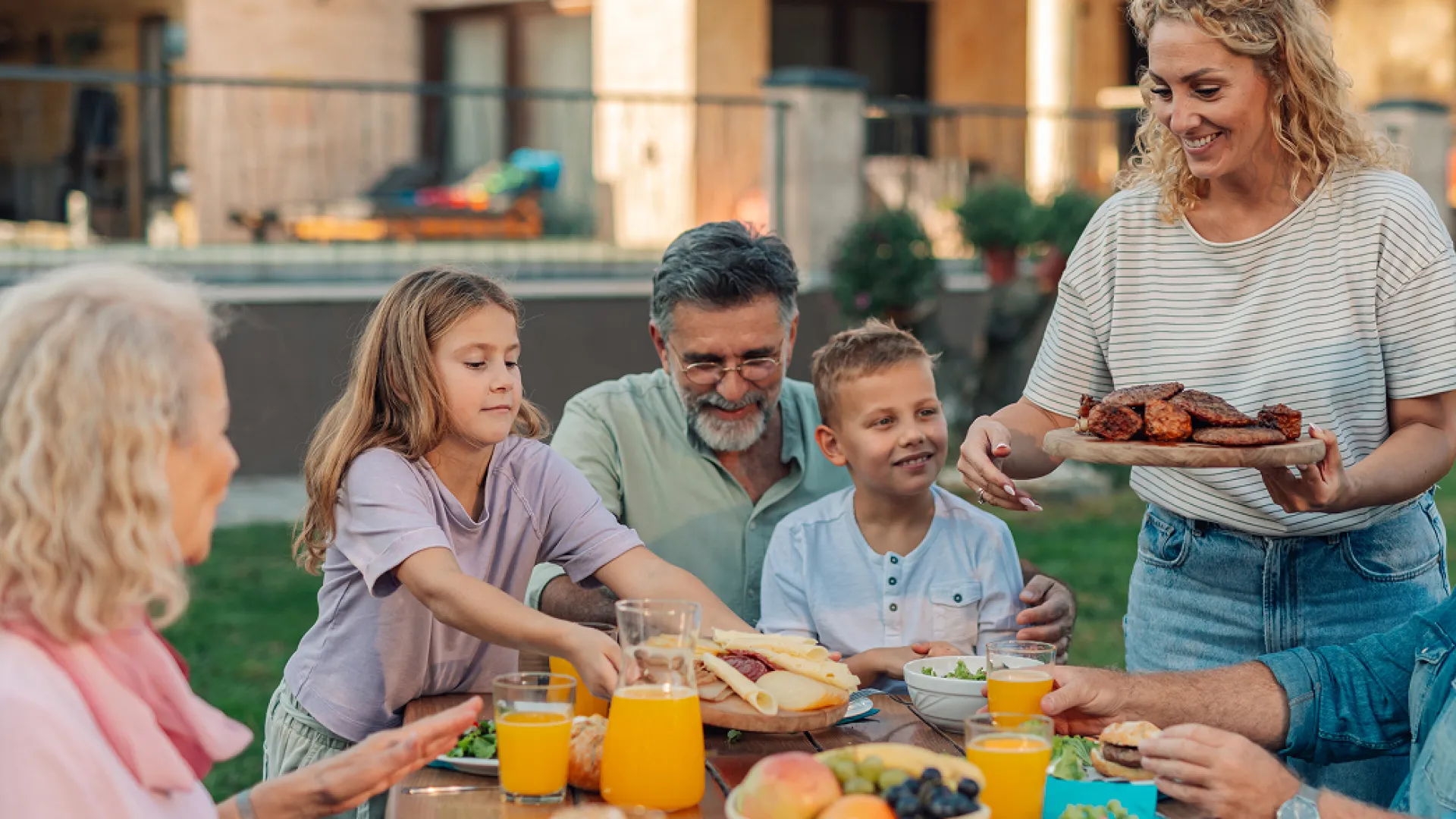 Multigenerational family enjoying a backyard meal with fresh food and drinks on a sunny day