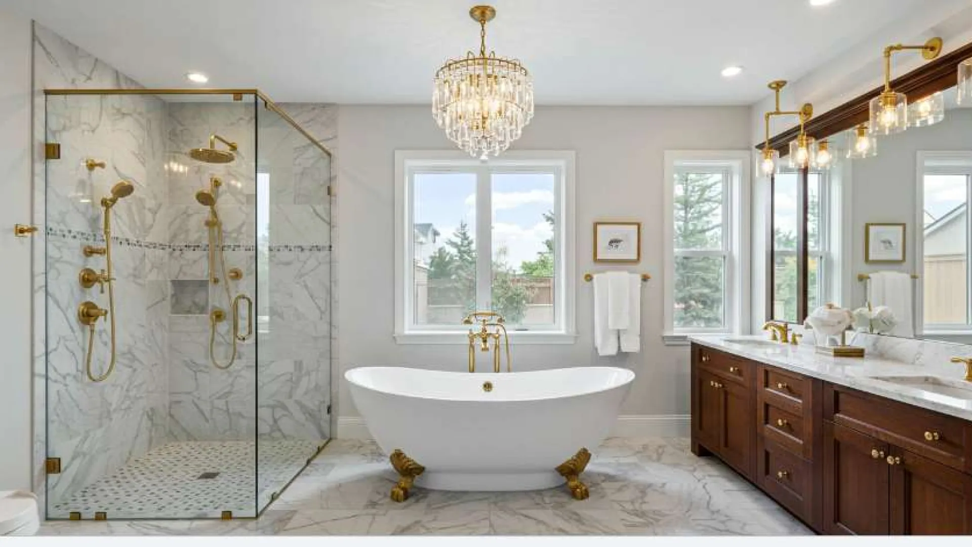 Luxury bathroom with freestanding clawfoot tub, glass shower with gold fixtures, chandelier, and double vanity.