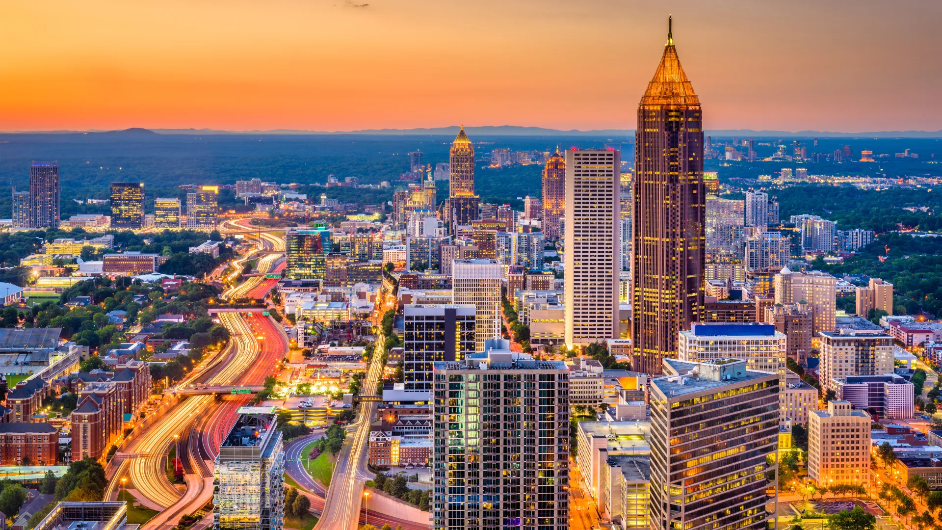 Sunset view of Atlanta city skyline with illuminated skyscrapers and busy highways in Georgia, USA