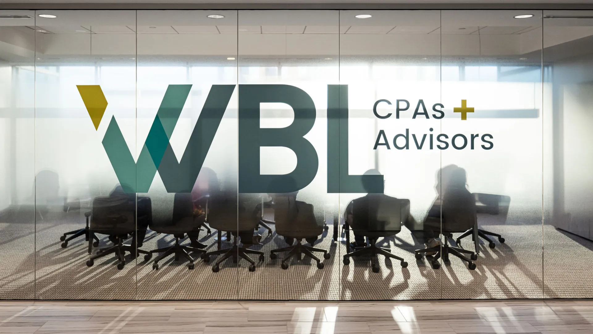 Office meeting room with large WBL CPAs and Advisors logo on glass wall and people silhouetted inside.