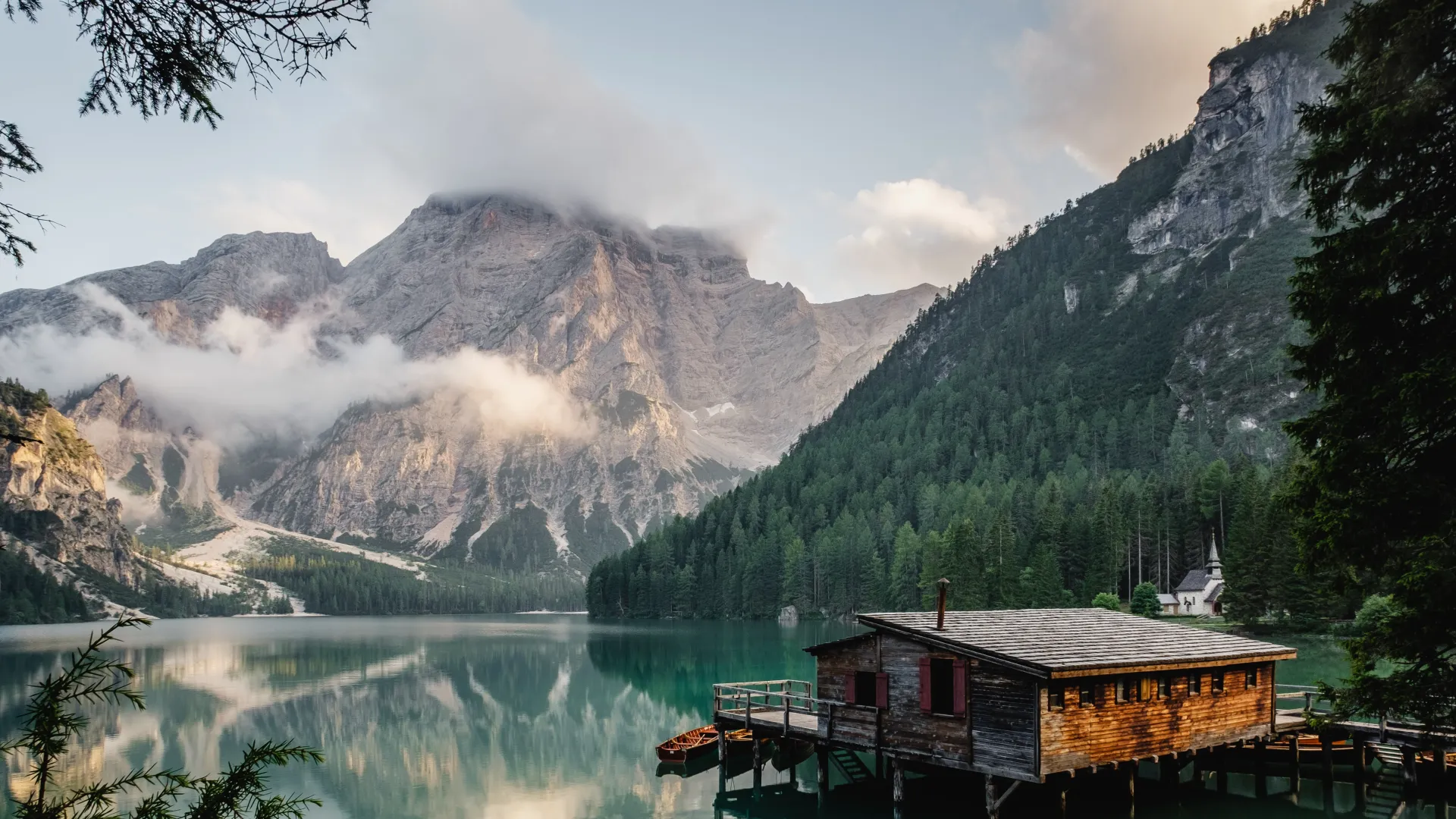 a house on a dock by a lake with mountains in the background