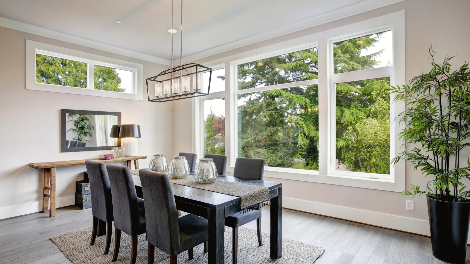 Modern dining room with dark wood table, six chairs, large windows, pendant light, and indoor plant.