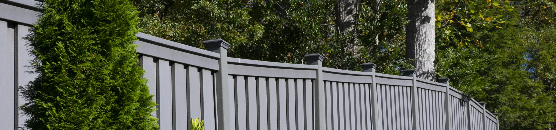 a white fence with trees and bushes around it