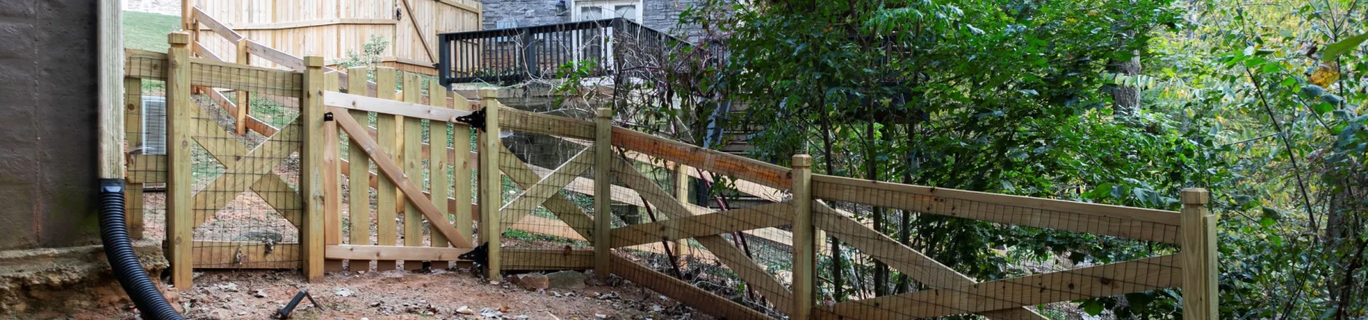 a fenced in yard with a wooden gate and a house