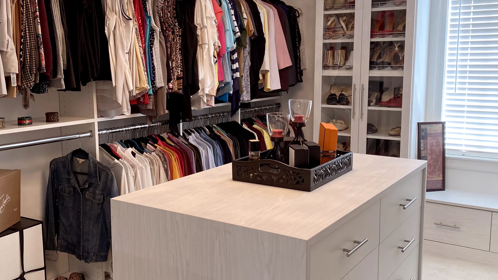 a room with a white cabinet and a white counter with a white shelf with clothes on it