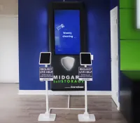 Midgard Self Storage help kiosks with touchscreens in a modern reception area with blue and green walls.