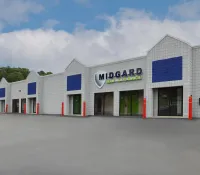 Exterior view of Midgard self storage facility with gray walls and blue accents under cloudy sky.