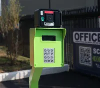 Green keypad entry system with black card reader at the entrance of a facility near an office sign.