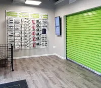 Interior of storage facility with green roll-up door and display wall of packing supplies and locks.