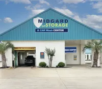 Midgard Self Storage and Car Wash Center building with drive-through car wash bay and palm trees under blue sky.