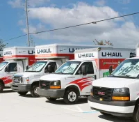 Row of U-Haul rental trucks parked outdoors under a partly cloudy sky, ready for moving service.