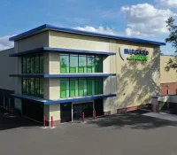 Modern Midgard Storage facility with green windows and secure gated parking under a blue sky.