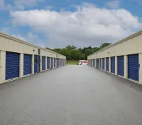 a road with a row of garages and a car parked on the side