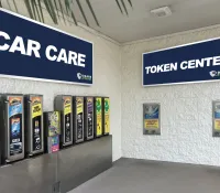 Car care product dispensers and token machines under Car Care and Token Center signs at self-storage facility.