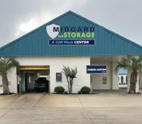 Midgard Self Storage and Car Wash Center building with a car exiting the wash under cloudy sky.