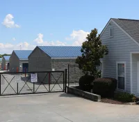 a building with a fence and bushes in front of it