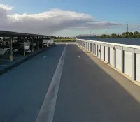 a road with a white fence and a white building with a blue sky