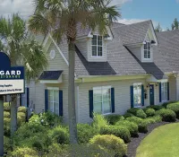 Midgard Self Storage facility with landscaping, palm trees, clear blue sky, and a large sign listing services offered.