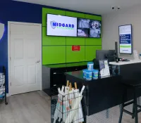 Midgard Self Storage office with green and blue decor, informative monitors, and packing supplies on display.
