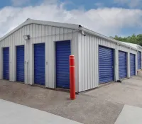 Exterior view of a self-storage facility with multiple blue roll-up doors and a clear sky above.