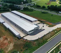 Aerial view of a large self storage facility with multiple white-roofed buildings near a highway and green fields.