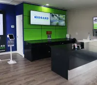 Modern storage facility lobby with black reception desk, green and blue wall panels, and digital signage