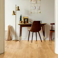 Minimalist home office with wooden desk, brown chair, gold floor lamp, light wood flooring, and wall decor.