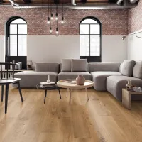 Modern living room with gray sectional sofa, wooden coffee tables, exposed brick wall, and large arched windows