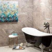Black clawfoot bathtub with ornate silver legs in a modern bathroom with gray marble tiles and abstract wall art.