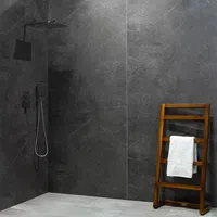 Modern shower area with dark gray stone walls, rainfall showerhead, and wooden towel rack with white towel.