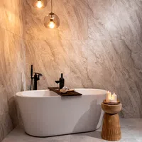 Modern bathroom with freestanding white bathtub, wooden candle holder, and warm ambient lighting