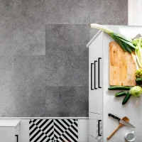 Modern kitchen countertop with fresh vegetables, wooden cutting board, knife, and mug on white surface