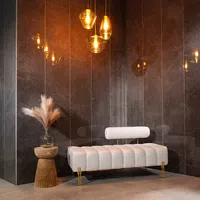 Modern white upholstered bench with gold legs beside wooden side table and hanging glass pendant lights