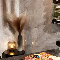Cozy corner with pampas grass in vase, lit candle, charcuterie board, and wine glass on marble surface