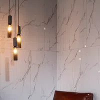 Modern interior with marble-patterned wall tiles and four hanging cylindrical pendant lights with warm glow.