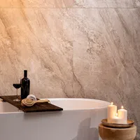 Relaxing bathroom scene with white bathtub, wooden tray holding wine and brush, and lit candles on stool.