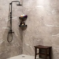 Modern shower with black fixtures, marble tile walls, corner shelves with toiletries, and a wooden shower bench.
