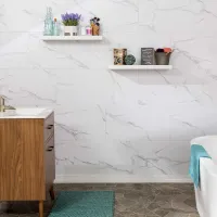 Modern bathroom with wood vanity, white marble tile wall, floating shelves, and teal bath mat and towel.