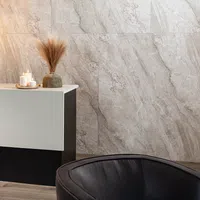 Modern interior corner with black leather chair, black and white cabinet, dried pampas grass, and candles on marble wall.