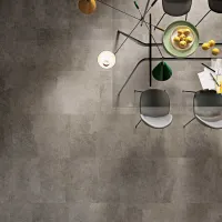 Top view of a modern dining table with black chairs, a green lamp, and a bowl of yellow lemons on a gray floor.
