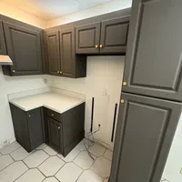 Modern kitchen corner with gray cabinets, white countertop, hexagonal floor tiles, and exposed power outlet with cords.