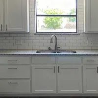Modern kitchen with white cabinets, granite countertops, subway tile backsplash, stainless steel sink, and window view.