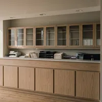 Modern office reception area with wooden cabinetry, glass-front shelves, and large windows letting in natural light