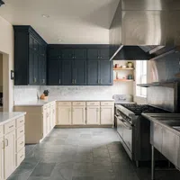 Modern kitchen with dark upper cabinets, white lower cabinets, stainless steel appliances, and open wooden shelves.