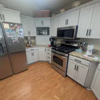 Modern kitchen with stainless steel appliances, light gray cabinets, granite countertops, and wood flooring.
