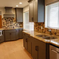 Modern kitchen with granite countertops, gray cabinets, stainless steel appliances, and diamond-patterned tile backsplash.