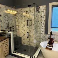 Modern bathroom with glass shower, floral tile walls, freestanding tub with wooden tray, and dark blue accents.