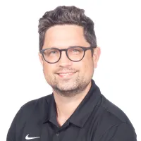 Man with glasses wearing a black PV Heating Cooling Plumbing polo shirt smiling against white background